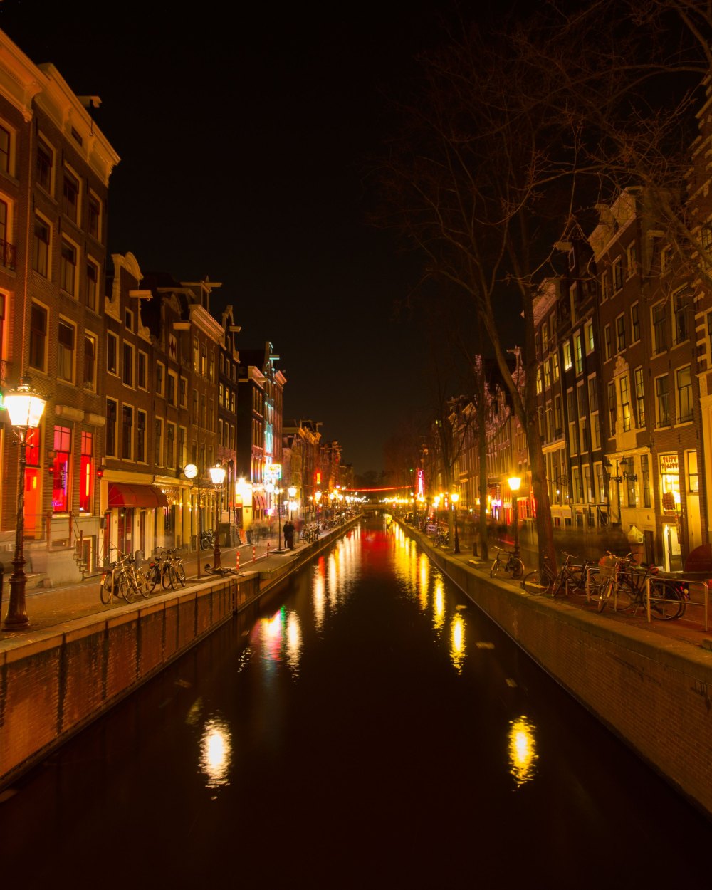 De Wallen bij nacht, met rode neonramen langs de gracht