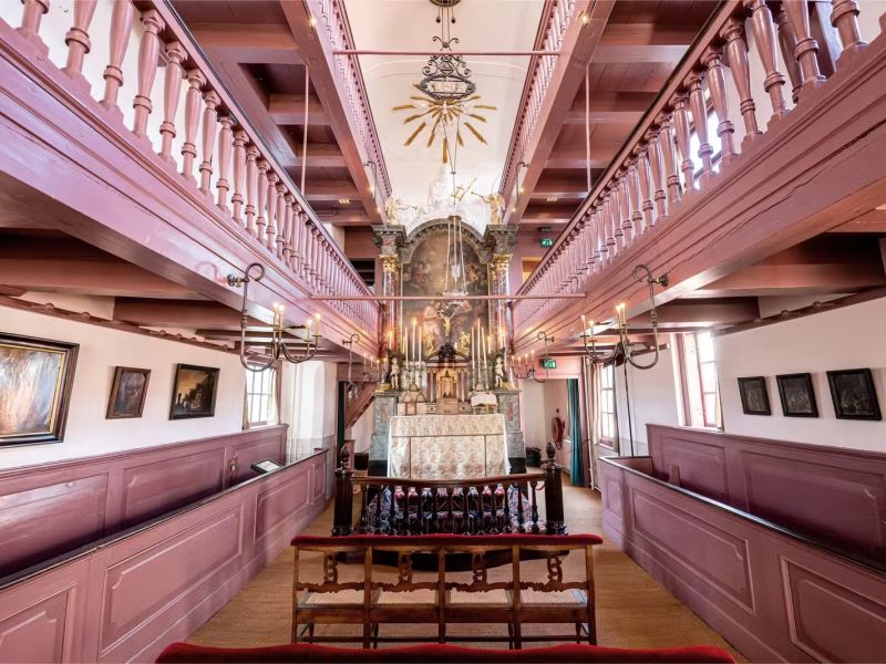 De zolderkerk van Ons' Lieve Heer op Solder met roze galerijen aan beide kanten en het altaar met schilderij aan het eind